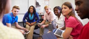 High school students and a teacher sitting in a discussion circle in a classroom