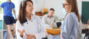 Two teachers talking and laughing together in a school staff room