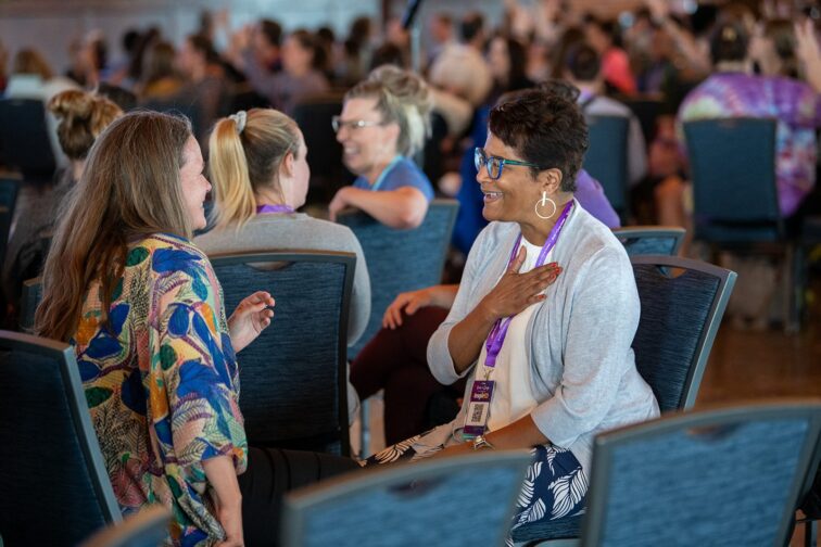 Two educators in a partner conversation at a Breathe for Change event, one with her hand on her heart